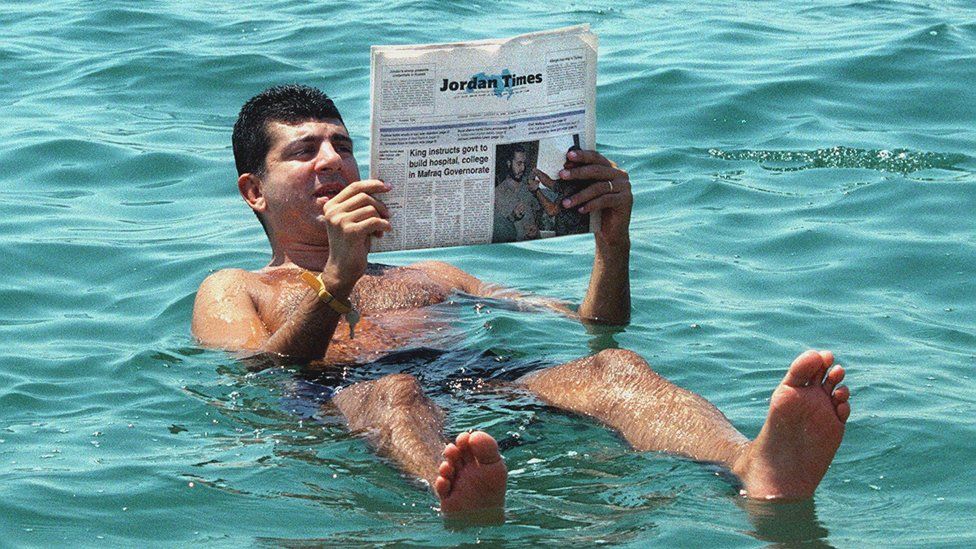 A man reads a newspapers while floating in the Dead Sea, southwest of Amman - 31 August 1999