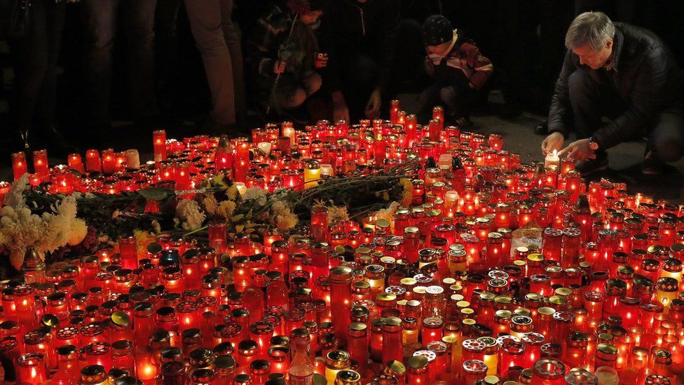 Romanian Prime Minister Dacian Ciolos (right) lights a candle for victims of the nightclub fire