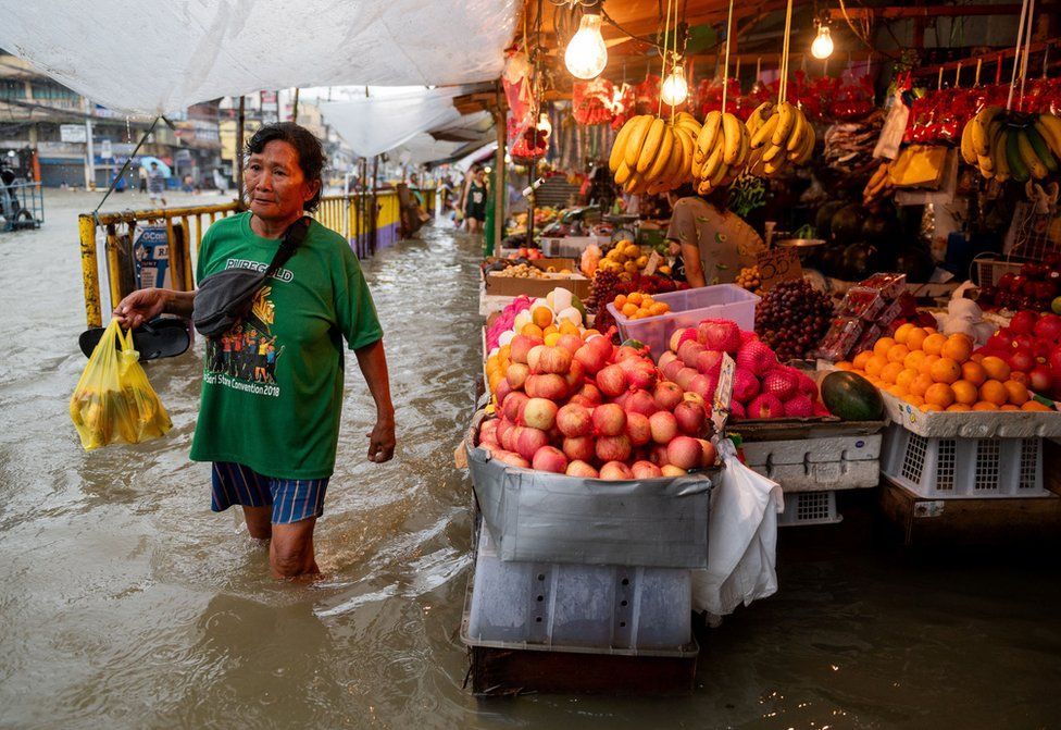 A woman walks past a flooded market caused by monsoon rains and the recent typhoon Doksuri, in Balagtas, Bulacan province, Philippines, July 29, 2023.