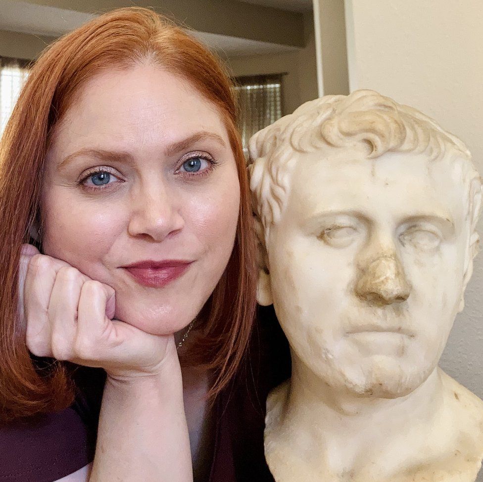Woman poses with Roman bust