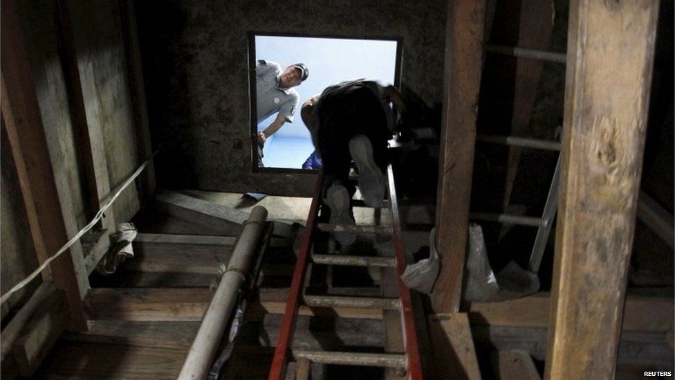 A police officer looks on as a television cameraman climb into a tunnel discovered by Mexican security forces, during a presentation to the media in Tijuana, on 2 August, 2015