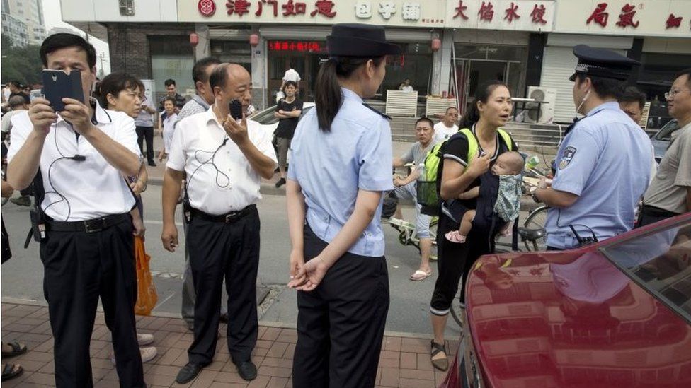 Plain clothes police film journalists and talk to relatives outside the court in Tianjin (2 Aug 2016)