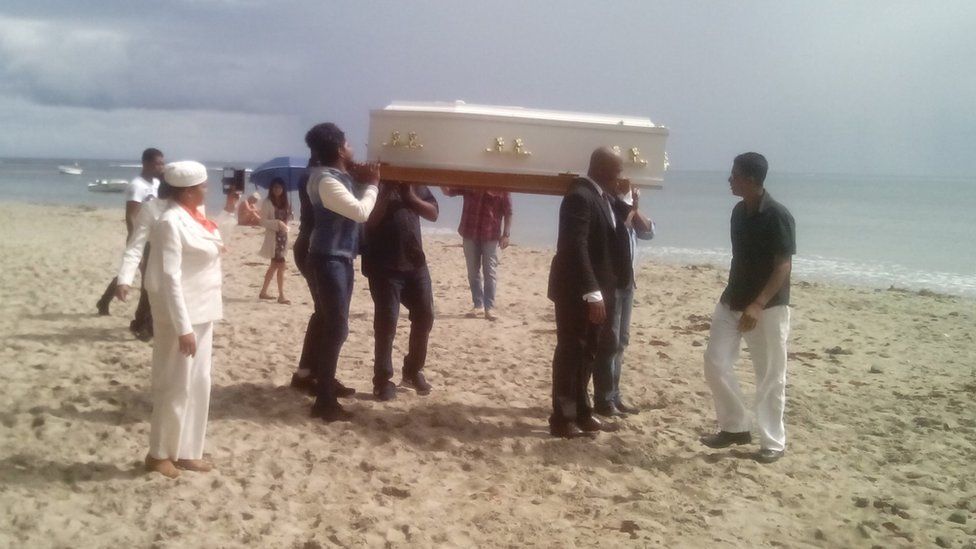 Coffin being carried on beach