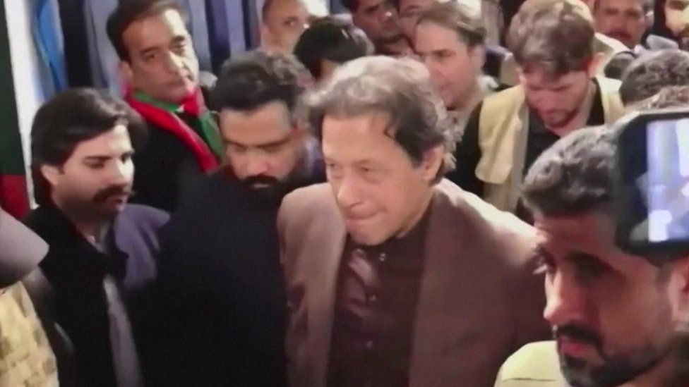 Imran Khan walks through a crowd on his way to deliver a speech