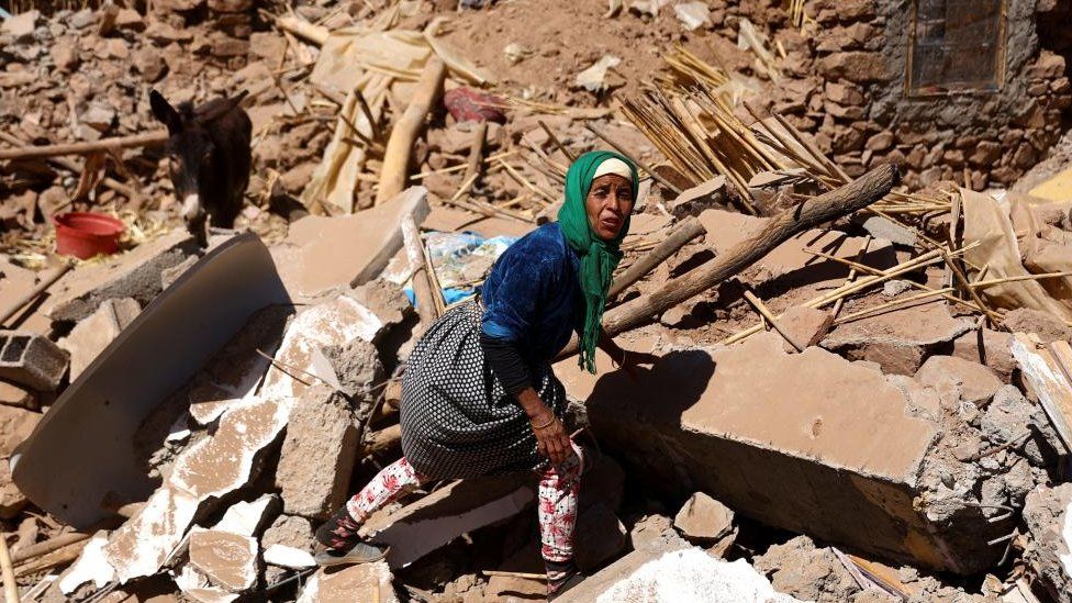 Khadijah Deaoune walks in the rubble next to her donkey, where her house once stood, as she tries to rescue her goat after the deadly earthquake in Tinmel, Morocco