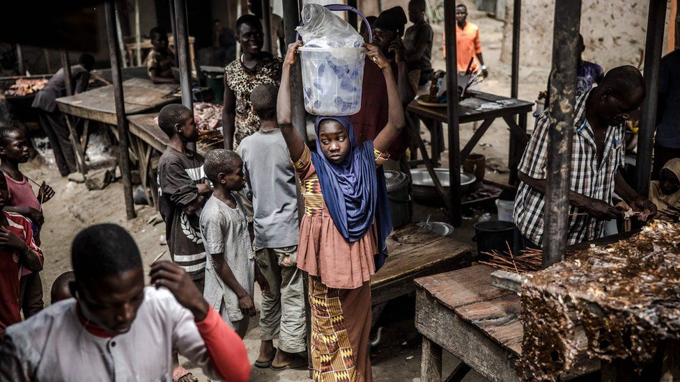 A girl selling water waits for costumers at a market