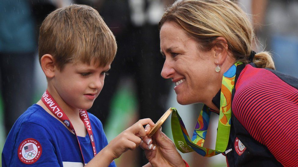 Gold medallist Kristin Armstrong (R) shows her medal to her son