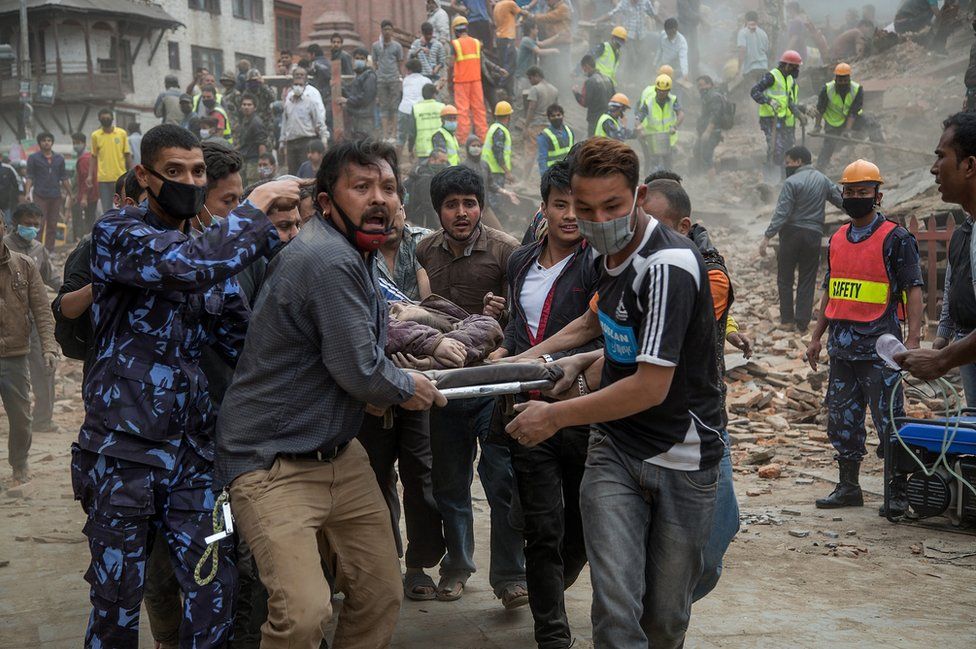 Emergency rescue workers carry a victim on a stretcher after Dharara tower collapsed in Kathmandu, Nepal