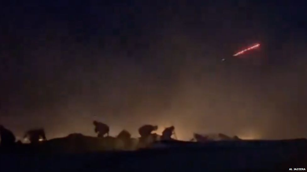 An image taken from an Al Jazeera video filmed close to the rear of the convoy showing people hiding behind vehicles and red tracer rounds in the sky