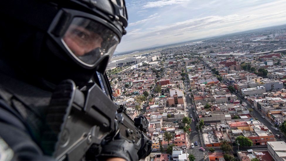 A policeman on board a helicopter as it flies over Mexico City in 2018