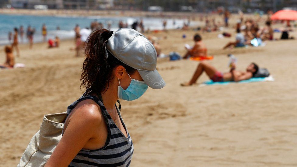 A woman with a face mask leaves the Las Canteras beach as some Spanish provinces are allowed to ease lockdown restrictions during phase two, amid the coronavirus disease (COVID-19) outbreak, on the island of Gran Canaria, Spain
