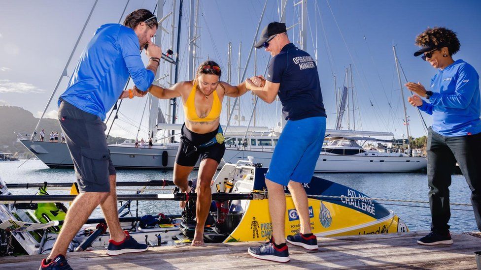 Lara Vafiadis is helped off her boat after rowing across the Atlantic