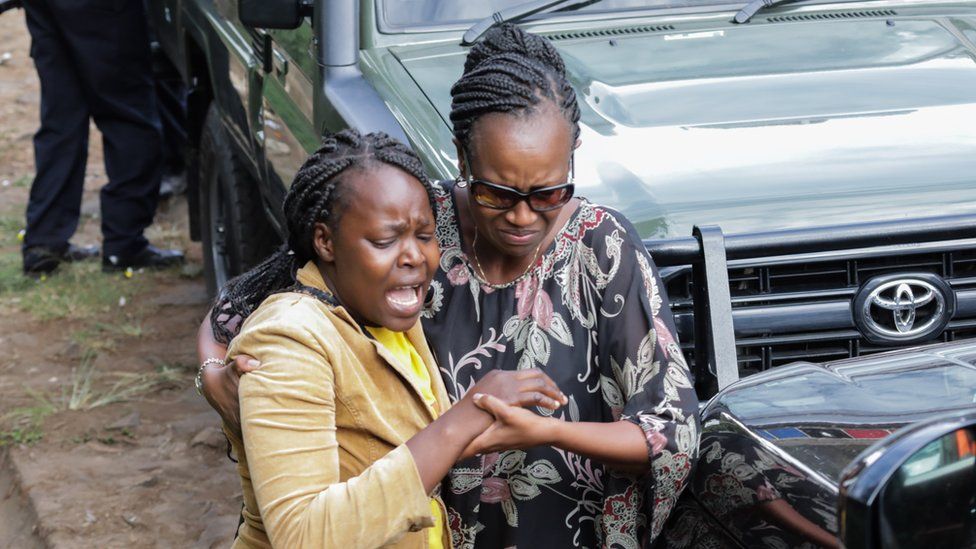 Kenyan woman caught up in the attack (L) led away by relative - 16 January