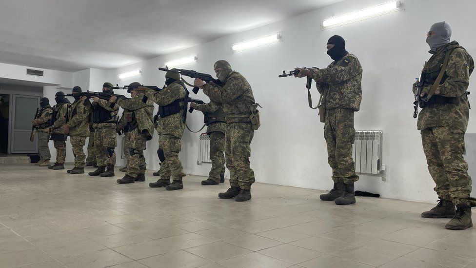 Soldiers in uniform, holding guns, training indoors in an undisclosed location