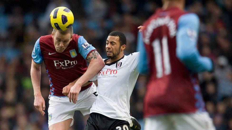 Richard Dunne of Aston Villa challenges Mousa Dembele of Fulham