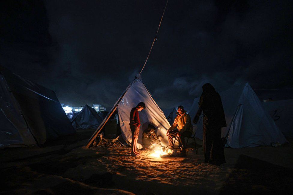 Displaced Palestinians, living in tents, light a fire to keep warm as they struggle with cold weather under limited means and difficult conditions during the fourth day of the humanitarian pause in Khan Yunis, Gaza on November 27, 2023.