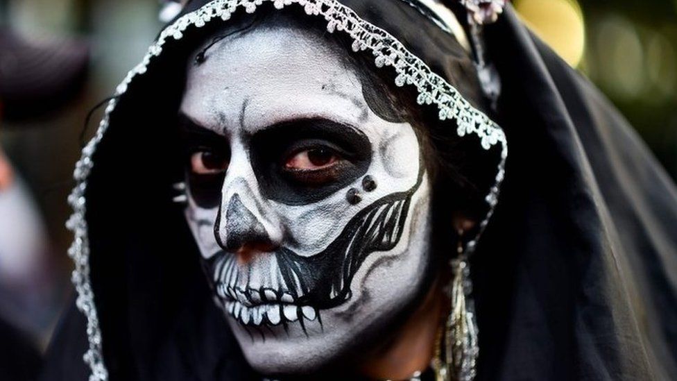 A woman wears a black hood and make-up during the Catrinas parade in Mexico City.