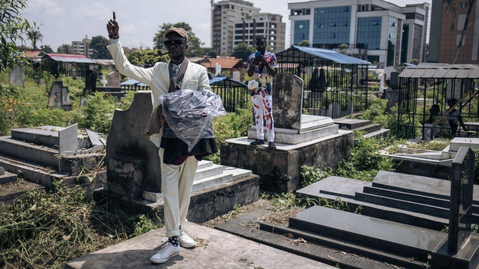 A man gestures on a grave during a gathering of sapeurs in a cemetery in Kinshasa, capital of the Democratic Republic of Congo, on February 10, 2023