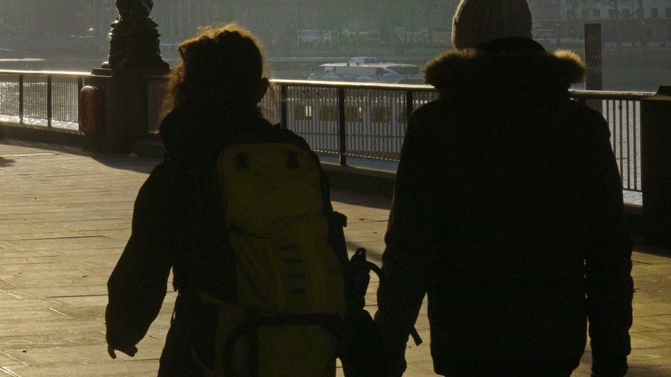 Silhouette of a couple from behind holding hands
