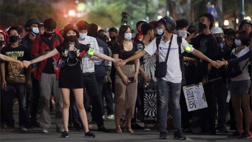 A group of protesters hold hands as they march through Bangkok