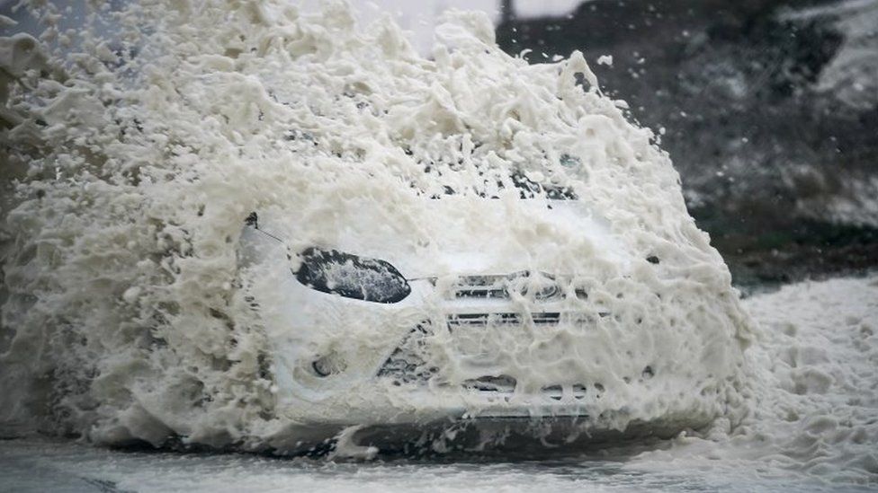 The winds whipped up sea foam into the paths of cars at Trearddur Bay, Wales