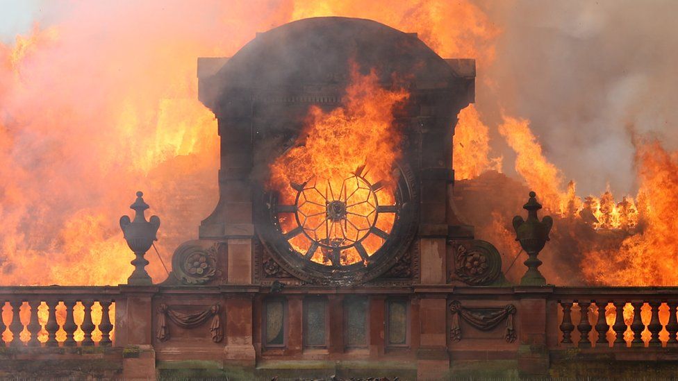 Flames burn through the clock at the top of the Bank Buildings