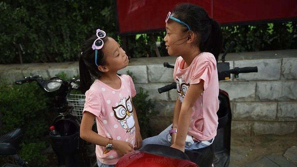 Two sisters play on their parents' electric scooter in Beijing on July 10, 2015.