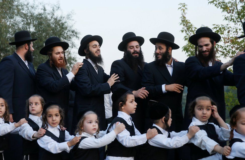 A line of Ultra-Orthodox Jewish pilgrims dance on a riverbank in Uman, Ukraine
