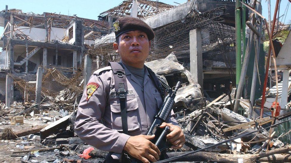 An armed Indonesian policeman guards what remains of a nightclub in the aftermath of the Bali bombing in October 2002.