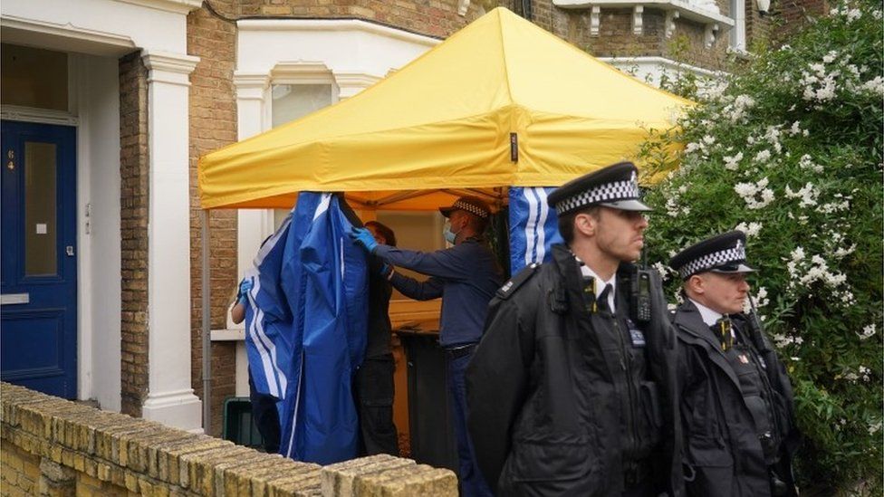 Police officers erect a tent outside a house in north London, thought to be linked to the murder investigation
