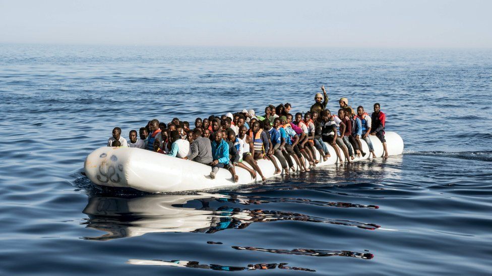 Libyan coast guardsmen standing in a dinghy carrying illegal immigrants during a rescue operation