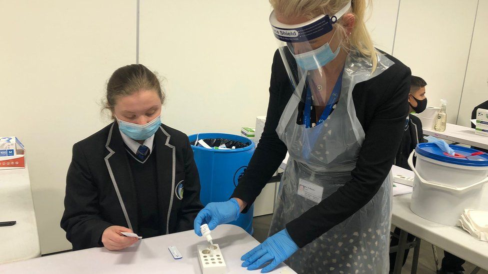 Pupil taking a lateral flow test with the help of an adult