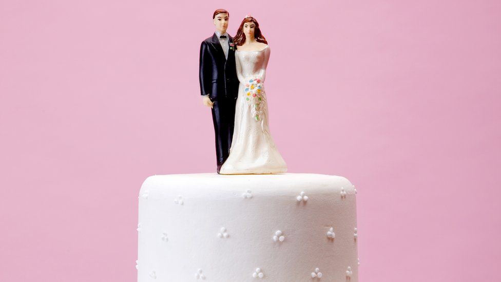 A bride and groom model on top of a wedding cake
