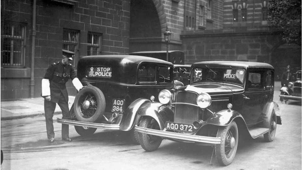 25th October 1933: Two police cars at Scotland Yard, London, with a new mechanised 'Stop, Police' sign, that can be operated from the steering wheel. (Photo by J. A. Hampton/Topical Press Agency/Getty Images)