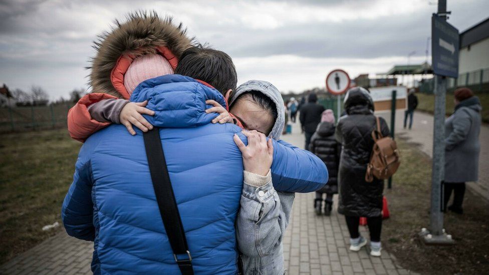 A man hugs his daughter and granddaughter after they crossed the border between Ukraine and Poland