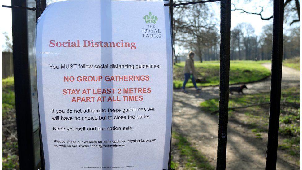 A sign issued by the Royal Parks advising on social distancing at an entrance to Richmond Park