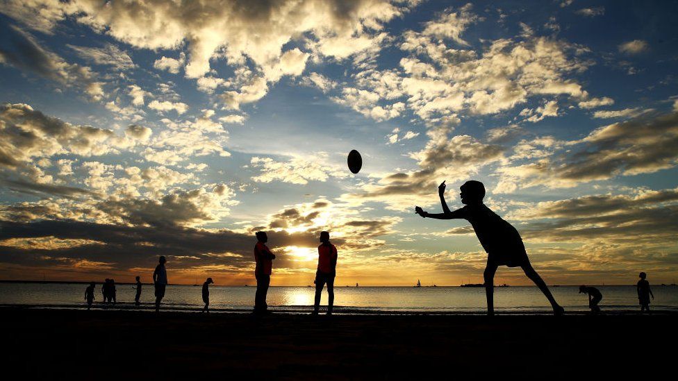 Boys play sport on a beach in the Northern Territory