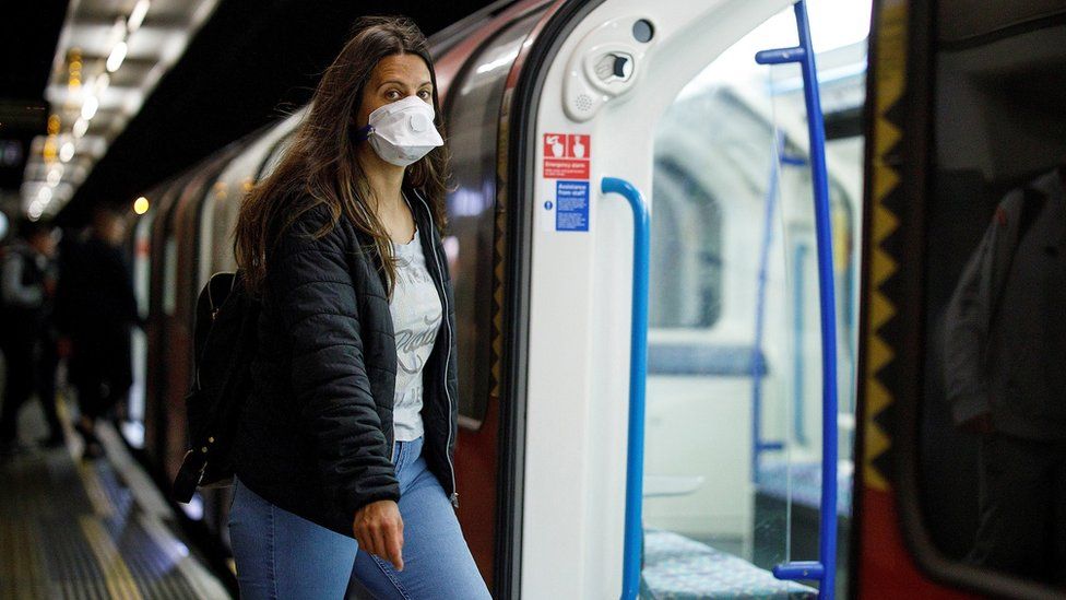 A person getting on the tube with a face covering on