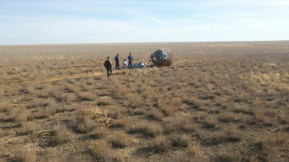 Specialists gather near the Soyuz capsule transporting U.S. astronaut Nick Hague and Russian cosmonaut Alexei Ovchinin