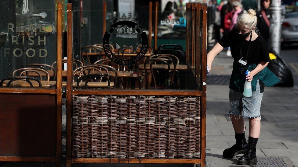 A restaurant worker cleans an outdoor seating area in Dublin