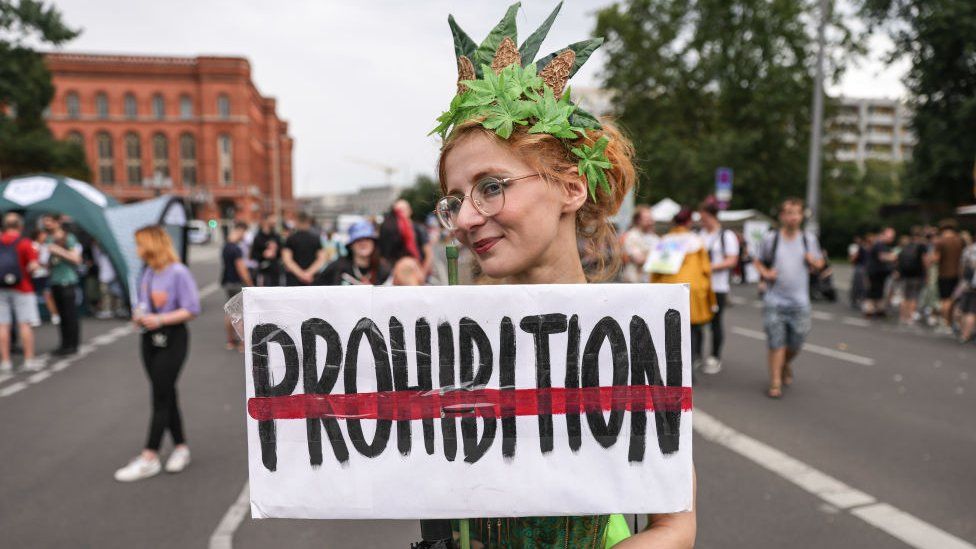 A costumed cannabis supporter holds a banner against prohibition during the annual Hemp Parade on August 12, 2023 in Berlin, Germany