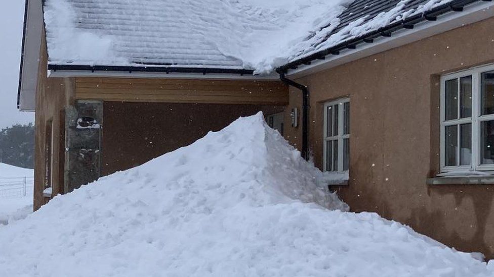Snow stacks up against a house in Lumphanan in Aberdeenshire