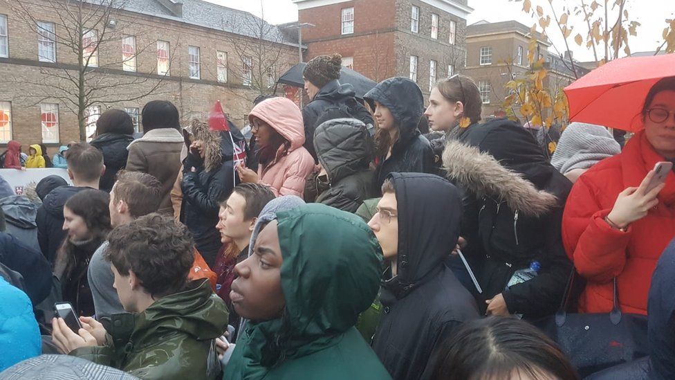 Crowds waiting in the rain outside the University of Leicester