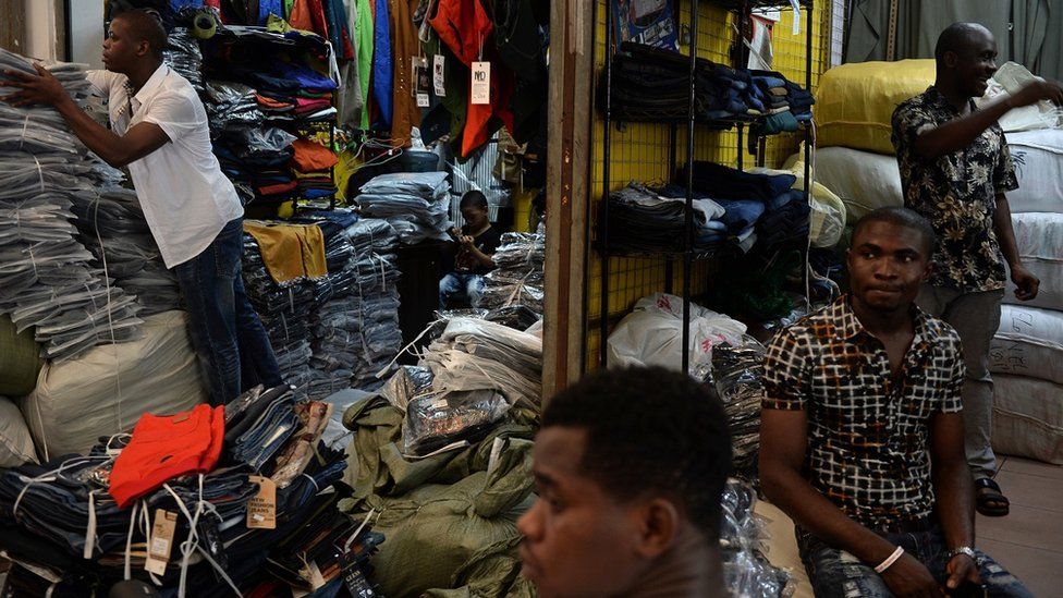 In a picture taken on August 26, 2013, Lamine Ibrahim (L) from Guinea works as his four-year-old son (back C) looks on at their shop inside a clothing wholesale market in Guangzhou