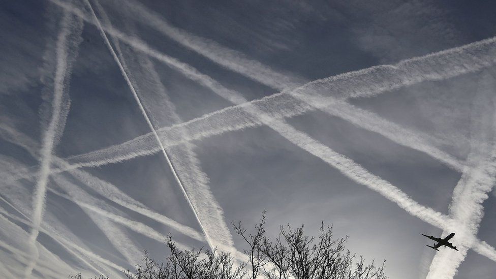 Инверсионные следы пересекаются в небе и виден самолет