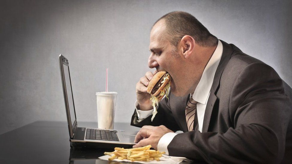 man eating over computer