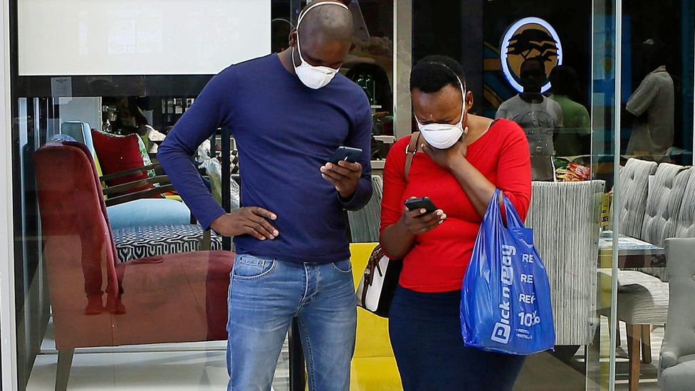 A couple wearing masks looking at their mobile phones in Pretoria, South Africa - 29 March 2020
