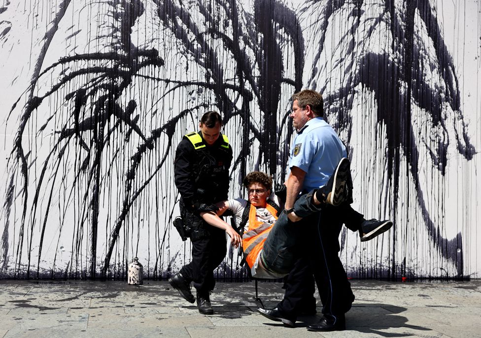 Police officers remove an activist of the "Letzte Generation" (Last Generation) after they spilled black liquid, symbolizing oil during a protest in Berlin, Germany, 22 June 2022.