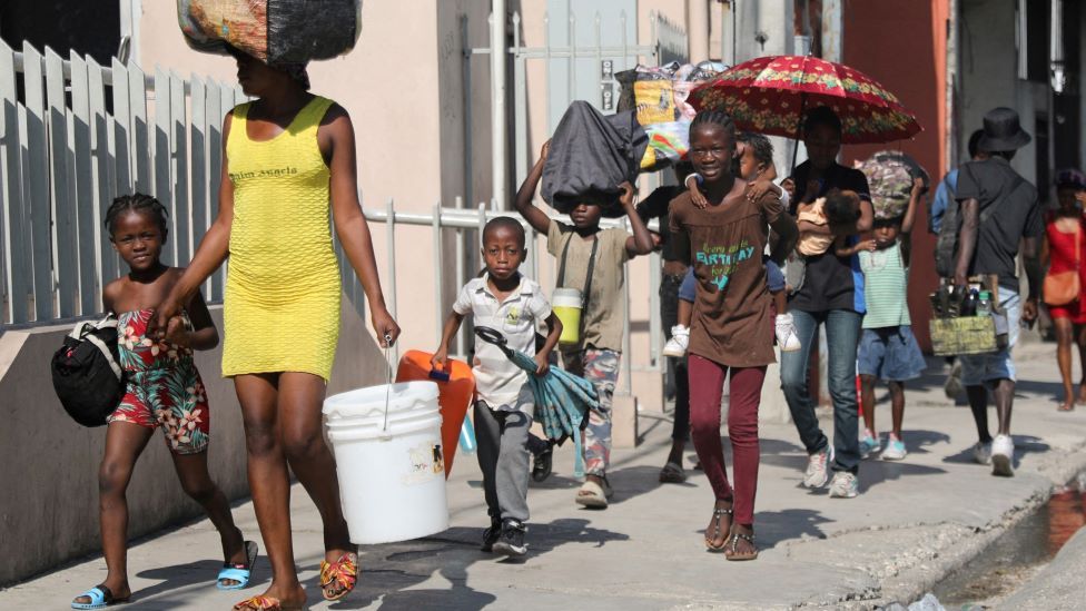 People walk towards a shelter with their belongings fleeing from violence around their homes, in Port-au-Prince, Haiti March 9, 2024