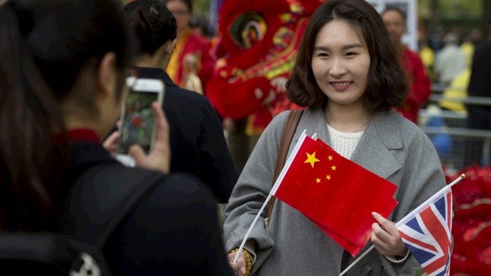 Members of the public wait on the Mall in central London before the official welcome ceremony at Buckingham Palace for President Xi of Chain in central London,